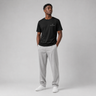 Man wearing a black t-shirt and gray pants on a gray background