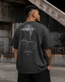 Man wearing a black t-shirt with a graphic design on the back in an industrial setting