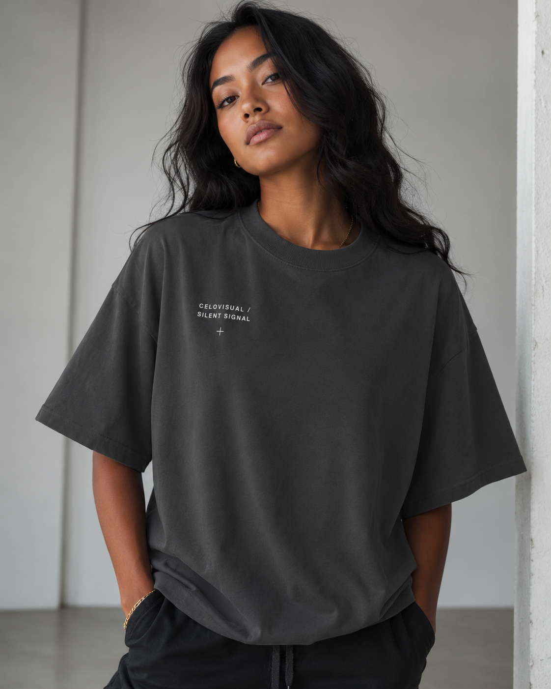 Person wearing a dark gray t-shirt with a logo on a plain background