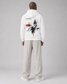 Person wearing a white hoodie with abstract design and text on the back, standing against a gray background