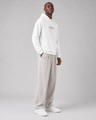 Person wearing a white hoodie and light gray pants on a plain background