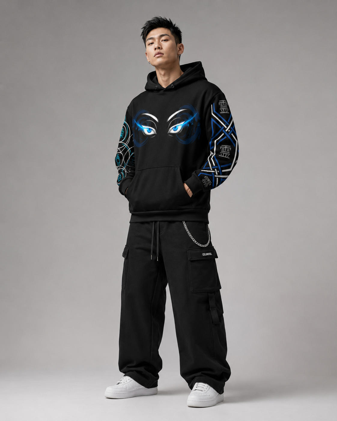 Person wearing a black hoodie with eye designs and black pants on a gray background