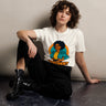 Person wearing a white t-shirt with a colorful graphic design sitting on a dark surface.